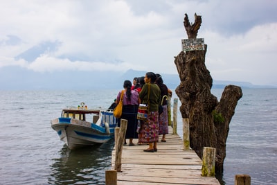 During the day, people standing on the wooden pier near the water
